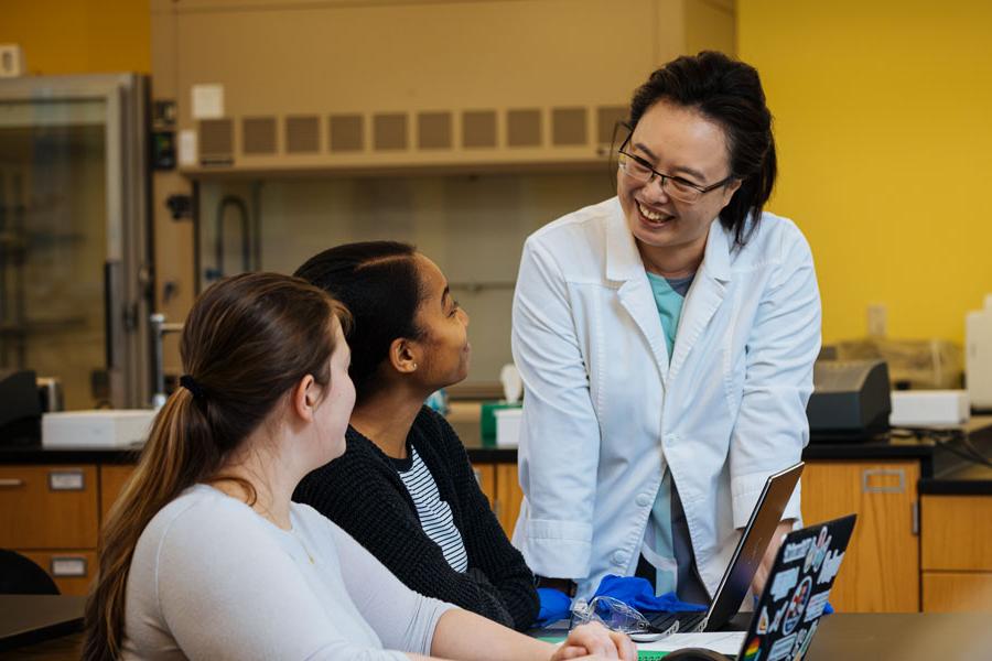 Students asking a professor a question in a science lab